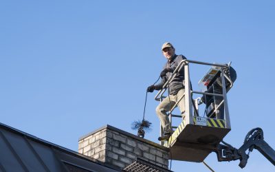 Raasiku, Estonia - May 04 2024: Worker in crane. Man on rental lift hoist cleaning the chimney of his own home. Fire safety measurements. Spring cleaning season.